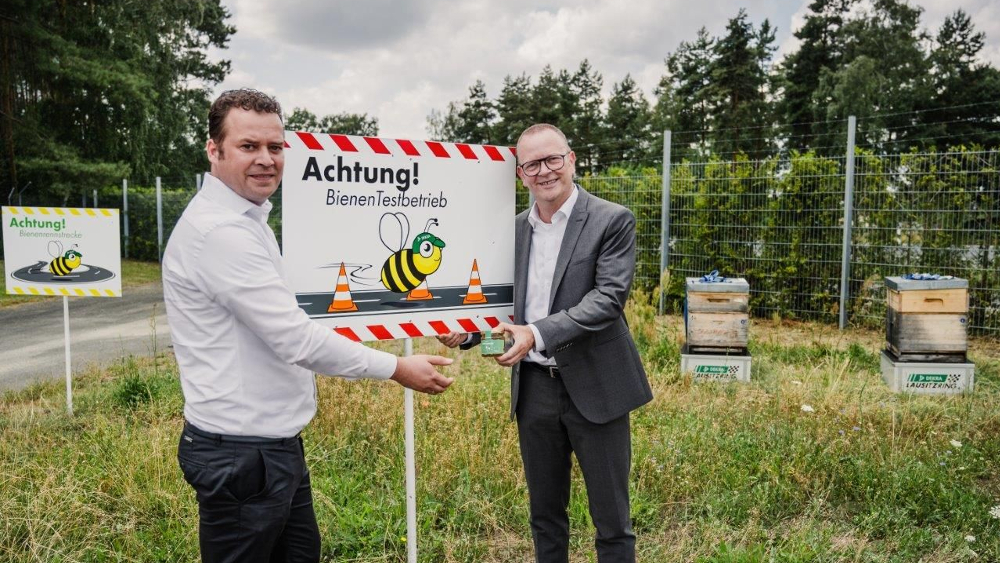 Guido Kutschera (rechts), Vorsitzender der Geschäftsführung der DEKRA Automobil GmbH, und Erik Pellmann, Fachbereichsleiter DEKRA Technology Center, freuen sich über die Bienenwiese am DEKRA Lausitzring und den eigenen Honig. ©DEKRA e. V. 