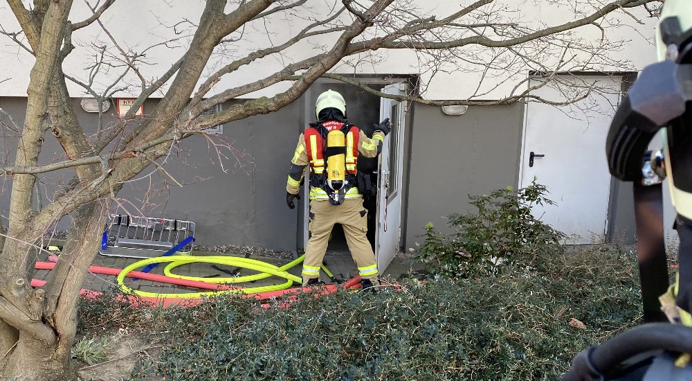 © Feuerwehr Dresden Symbolbild: Ein Feuerwehrmann unter Atemschutz öffnet die Tür zum verrauchten Kellerbereich in einem Wohnhochhaus.