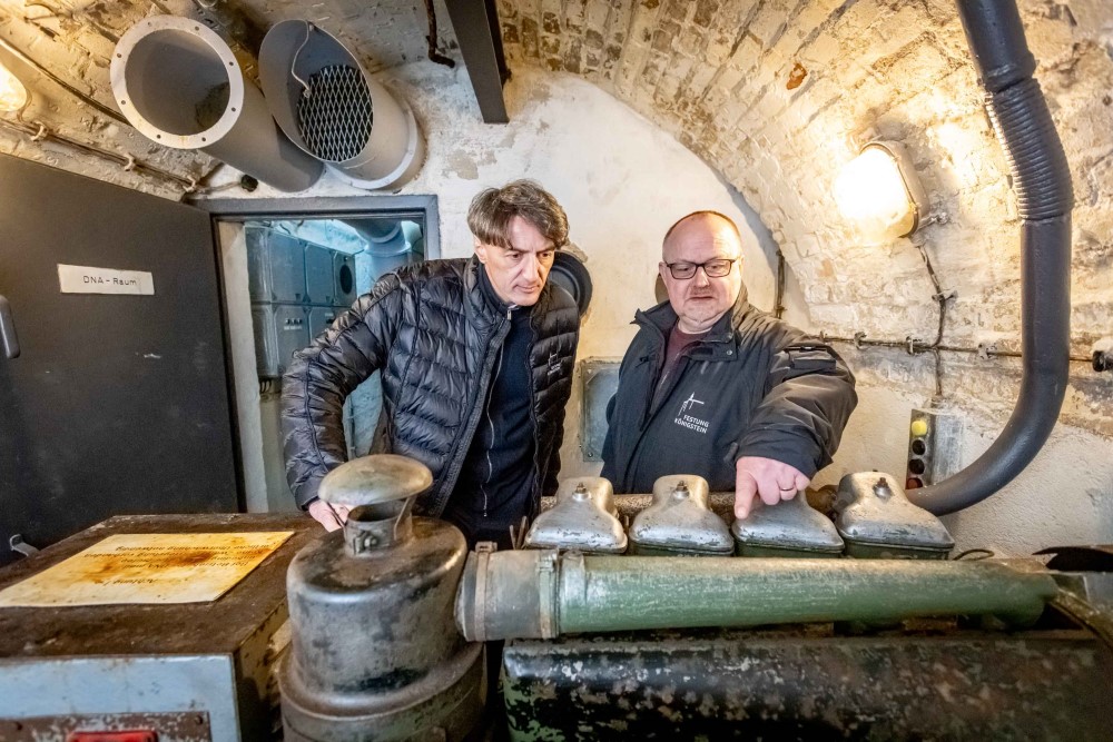 Festungschef Dr. André Thieme (l.) und Kurator Ingo Busse am Notstromaggregat des einstigen DDR-Bunkers. Foto: Marko Förster/Festung Königstein gGmbH 