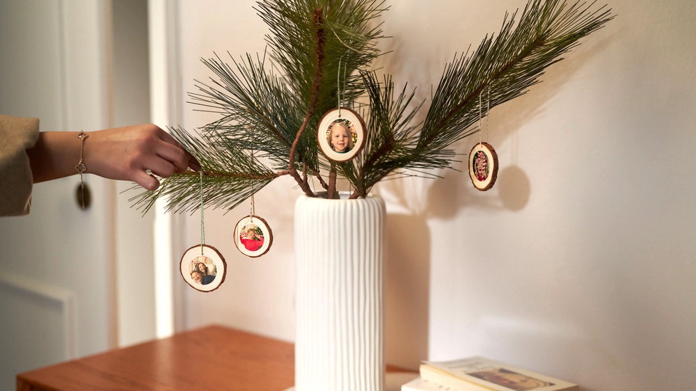 Einfach und schnell kreativ werden: Fotosticker lassen sich auf eine Holzscheibe kleben und mit einer Schnur an einem Tannenstrauß befestigen. Foto: DJD/www.cewe.de