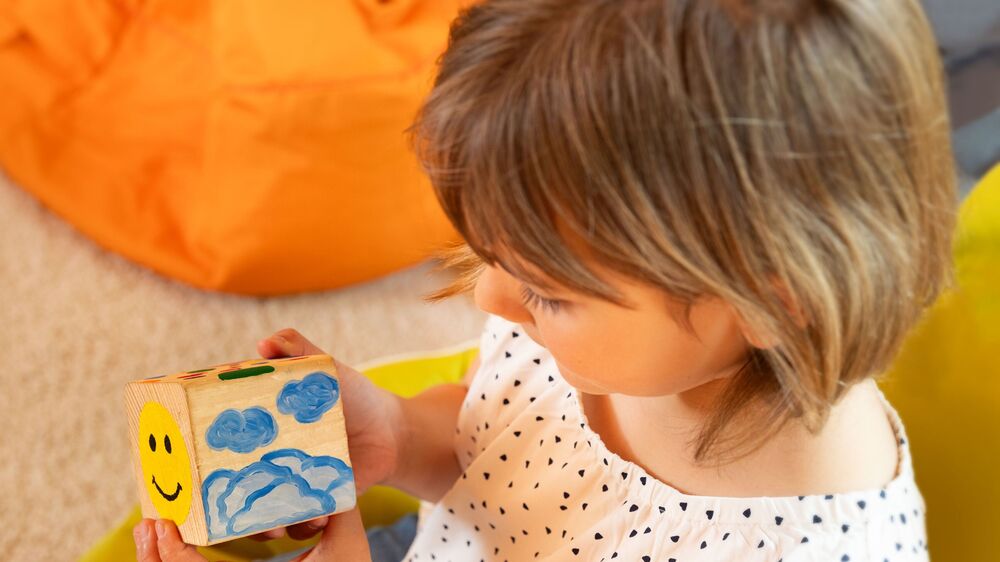 Kind mit dem Gefühlwürfel, welcher genutzt wird, um einen Austausch zu vereinfachen Foto ©Johanniter Dresden/ Anne Kaiser